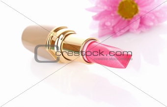 New lipstick and pink flower on white background