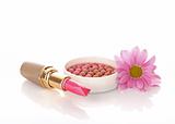 New lipstick and pink flower on white background