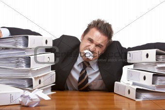 Stressed business man is frustrated in office between folder sta