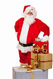 Santa Claus standing behind Christmas gift boxes and leaning on 