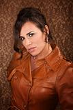 Pretty woman in leather coat on gold background