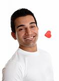 Flirtatious man holding a love heart between his teeth