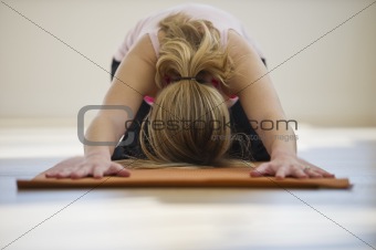 woman doing yoga on mat in studio