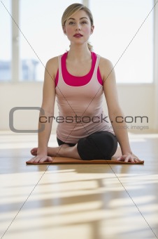 woman doing yoga on mat in studio