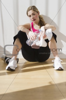 female sitting against wall in after workout