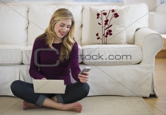 female in livingroom with laptop and cell phone