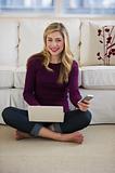 female sitting on floor with cell phone and laptop