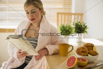 female with breakfast and newspaper in kitchen