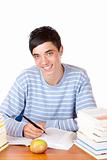 Young happy handsome male student sitting on desk learning with 