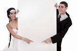 Bride and groom pointing at blank board