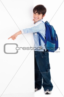 Young kid happily standing behind the board and pointing to empty space
