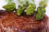 closeup of a beef steak with green asparagus on a white background