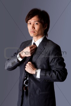 Successful Asian business man fixing tie