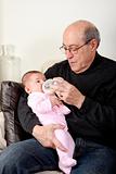 Grandpa bottle feeding baby girl