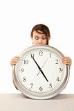 Woman at work holding up large office clock
