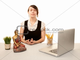 Pretty young woman meditating at her desk