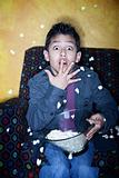 Young Hispanic boy with popcorn watching television