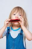 boy with long blond hair playing harmonica