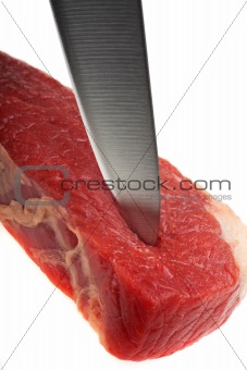 kitchen knife cutting through a raw steak