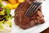 closeup of a silver fork on a steak