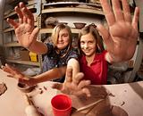 Cute young girls in a clay studio holding up their hands