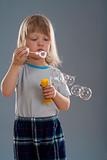 boy with long blond hair looking at big soap bubble - isolated on gray