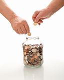 Senior hands collecting coins in a glass jar