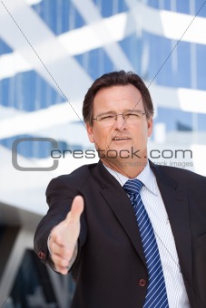 Handsome Businessman in Suit and Tie Holds Out His Hand To Shake Outside of Corporate Building.