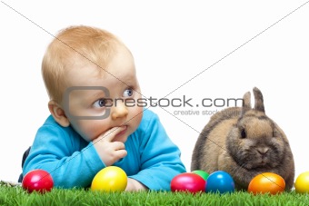 Cute young child with Easter bunny and Easter eggs in meadow