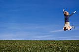 A pretty woman jumps for joy in a field