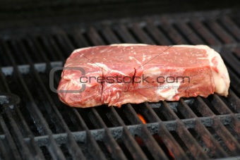 Raw steak on a BBQ grill