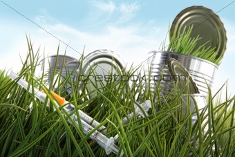 Syringe needles and food cans left in the grass 