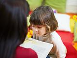 female teacher reading book to little girl