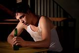 Depressed young man with bottle of beer