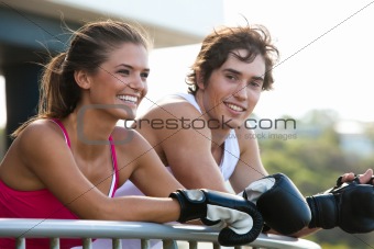 Young Couple in Boxing Gloves Leaning on Railing