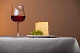 piece of cheese,a bunch of grapes and red wine