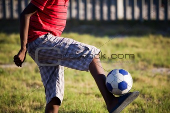 Teenage boy kicking soccer ball