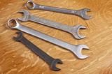 Four wrenches on a wooden background.