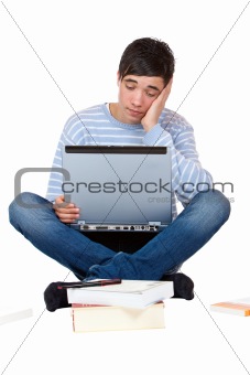 Young handsome student with books and laptop is tired of learning
