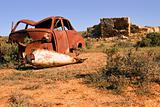 an old rusting car and ruins in the desert