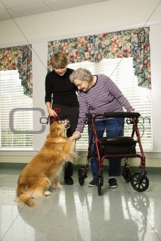 Elderly woman petting dog with middle-aged daughter.