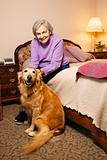 Elderly Caucasian woman in bedroom with dog.