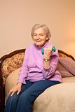 Elderly Caucasian woman lifting weights on bed.