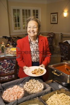Elderly Caucasian woman with dish in buffet line.