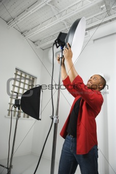 Young male adjusting studio lights.