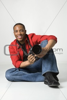 Young male sitting on floor with camera.