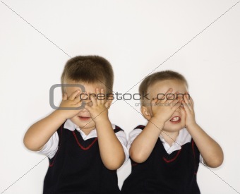 Male twins with hands over eyes.