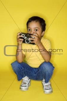 Male child kneeling with camera.