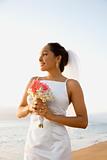 Bride holding bouquet on beach.
