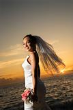 Bride holding bouquet on beach.